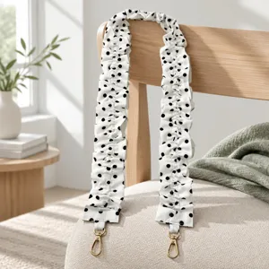 Detailed shot of white polka dot scrunchie strap with gold metal clasps for bag or phone.