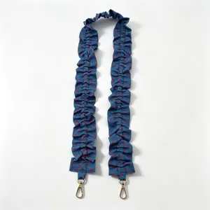Close-up detail view of the blue denim ruffled bag strap featuring red polka dots and gold clasps.