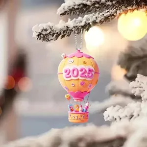 Primo piano del ciondolo a mongolfiera 2025 su ramo di pino innevato, decorazione festiva.