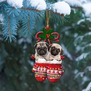 Vue détaillée des mignons chiots carlins dans des mitaines rouges de Noël en acrylique pour sapin.