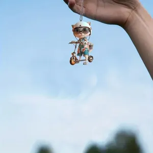Detail shot of cute cartoon cat acrylic pendant hanging against a clear blue sky outdoor.