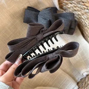 Détail de pince à cheveux nœud en tissu gris foncé, accessoire élégant automne hiver.