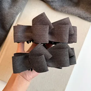 Pince à cheveux nœud gris foncé, élégant accessoire en tissu chevron pour coiffure élégante.