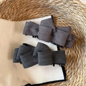 Détail de pince à cheveux nœud en tissu chevron gris, accessoire chic et élégant hiver.