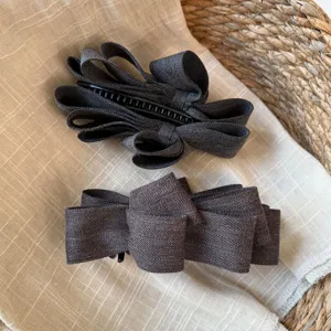 Élégante pince banane pour cheveux avec nœud gris, accessoire de coiffure tendance automne hiver.