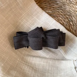 Détail de gros plan de pince à cheveux nœud en tissu gris foncé avec texture à chevron.