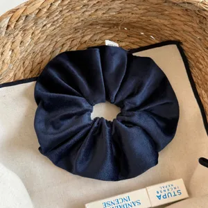 Gedetailleerd overzicht van een donkerblauwe fluwelen haarelastiek in een geweven mandje.