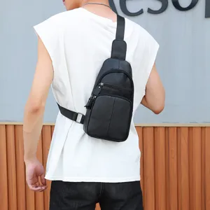 Detail shot of the men's black leather chest bag showcasing zipper pockets and adjustable strap.