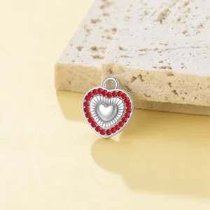 Detalle de primer plano del colgante de corazón de acero inoxidable con pedrería roja.