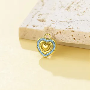Detalle de colgante de corazón dorado con cristales azules, ideal para abalorios DIY.
