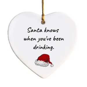 White ceramic heart Christmas tree hanging ornament with funny holiday quote and Santa hat.