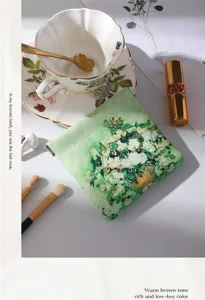 Detailed view of the aesthetic green floral cosmetic pouch in a lifestyle setting, compact size.