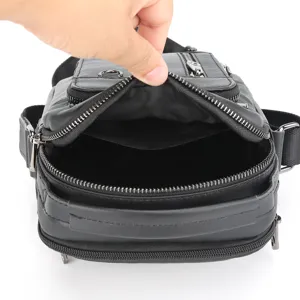 Detail view of the black leather chest bag interior, showing multiple zipper compartments.