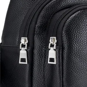 Close-up detail of black genuine leather chest bag showing smooth metal zippers and fine grain.