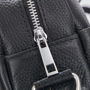 Close-up detail shot of black leather men business bag showcasing silver metallic zipper and texture.
