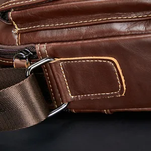 Close-up detail of brown genuine leather men's shoulder bag with durable metal hardware.
