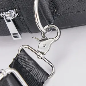 Close-up detail of silver metal hardware clasp, D-ring, and black leather bag strap.