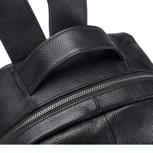 Premium black leather backpack detail close-up showing fine pebble grain texture and zipper.