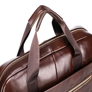 Close-up detail of dark brown leather business briefcase handle and zipper texture.