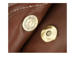 Close-up detail of vintage leather men's bag magnetic snap button, premium cowhide texture.