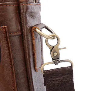 Gedetailleerde close-up van het metalen beslag van een bruine leren tas met stiksels.