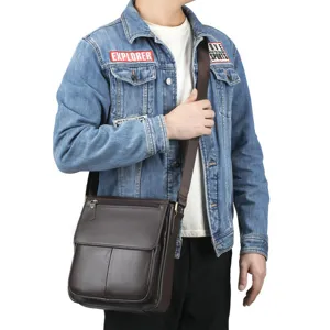 Close-up view of mens brown leather crossbody bag worn by model, showing detailed flap & strap.