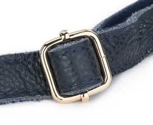Close-up detail of dark blue leather bag strap with a gold metal buckle. Premium quality.
