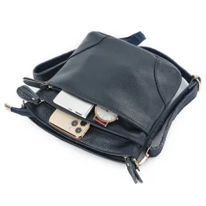 Detail view of dark blue genuine leather shoulder bag showing interior space and zipper pockets.