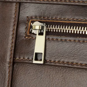 Close-up detail of genuine leather men's business bag zipper and fine stitching texture.