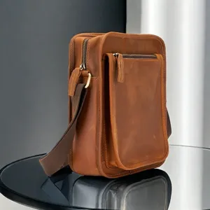 Detailed view of genuine crazy horse leather vertical messenger bag with canvas strap.