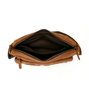 Close-up detail of the open brown vintage leather messenger bag interior and zipper pockets.