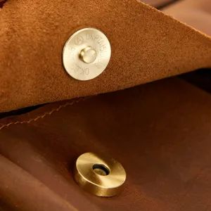 Vintage brown genuine leather messenger bag magnetic snap metal hardware detail closeup