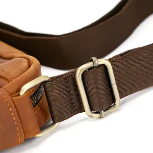 Men's leather messenger bag strap buckle detail close-up, durable canvas and vintage hardware.