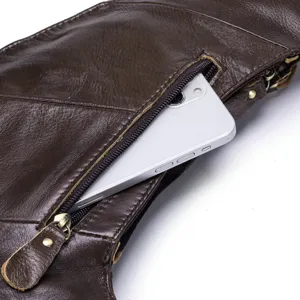 Détail en gros plan d'un sac de poitrine en cuir véritable marron foncé avec poche zippée.