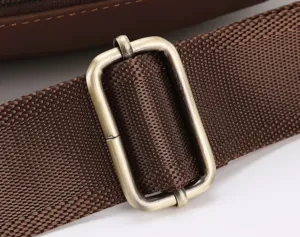 Close-up detail shot of the durable brown adjustable shoulder strap and vintage metal buckle.