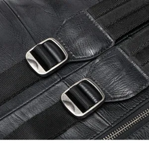 Close-up detail of genuine leather backpack hardware, metal buckle, and strap texture.