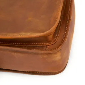 Close-up detail of vintage crazy horse leather messenger bag with neat stitching texture.