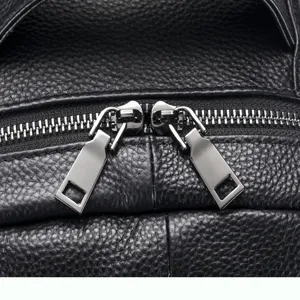 Close-up of premium black leather men backpack detail, showing durable metal zippers.
