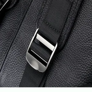Detailed view of black leather backpack metal buckle and durable woven strap hardware.