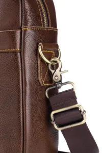 Close-up detail of men's leather bag strap connection and bronze metal hardware.