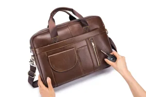 Leather briefcase detail view, brown cowhide texture, metal zipper and sturdy handles.