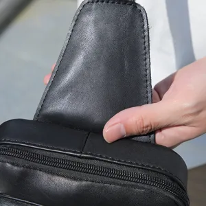 Detalle de bolso de pecho en cuero genuino, elegante bandolera vintage negra para hombre.