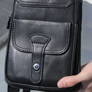Detalle de primer plano de bolso pecho hombre de cuero negro, costuras finas y cierre metálico.