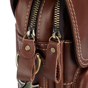 Close-up detail of men's genuine leather messenger bag zipper and heavy stitching hardware.
