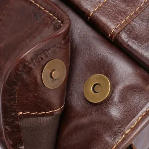 Vintage genuine leather messenger bag detail showing magnetic snap closure and texture.
