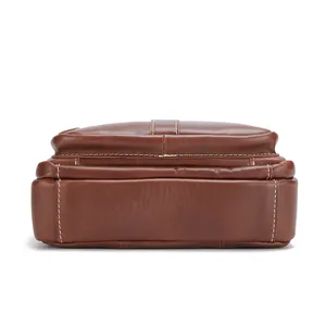 Brown leather men bag bottom detail close-up, premium cowhide texture, fine contrast stitching.