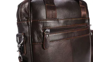 Men leather briefcase detail shot, brown cowhide shoulder bag texture close up view.