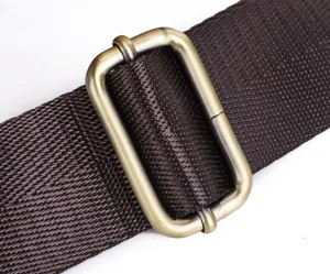 Close-up detail of dark brown woven strap with vintage brass metal buckle adjuster loop.