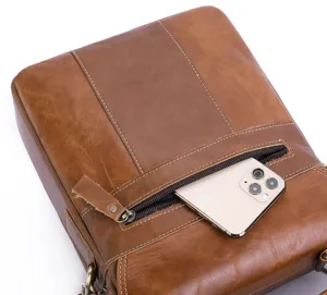 Detail view of men's genuine leather messenger bag front zipper pocket and fine stitching.