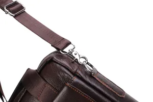 Men's leather briefcase detail shot, brown cowhide texture, metal hardware and strap.